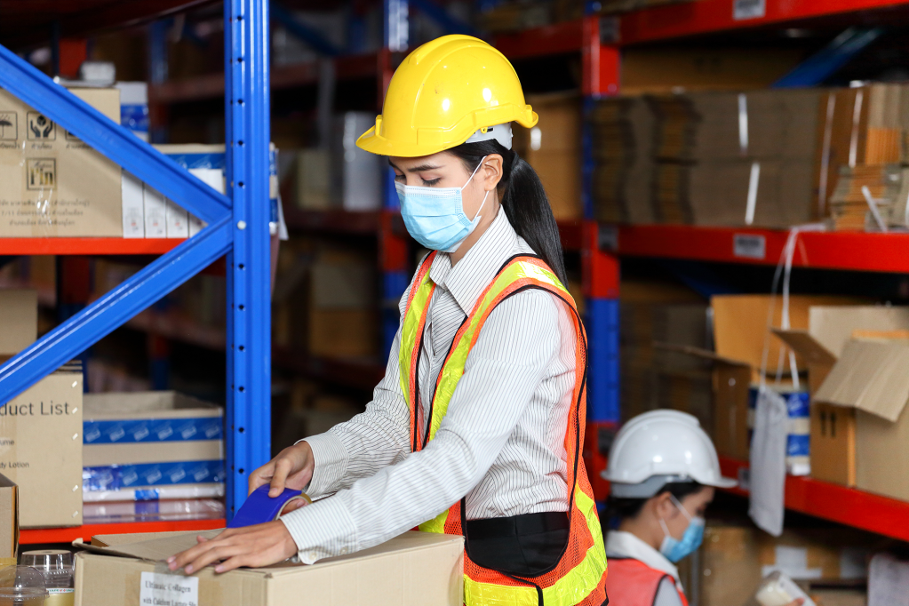 A woman in a safety vest and harness helps a business with their shipping processes