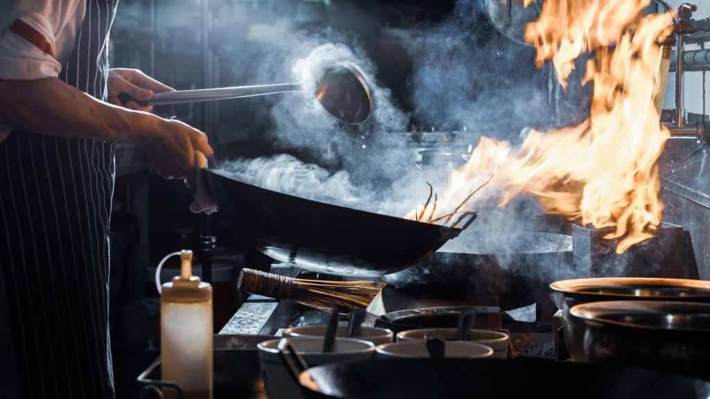 A chef uses a wok in a professional restaurant
