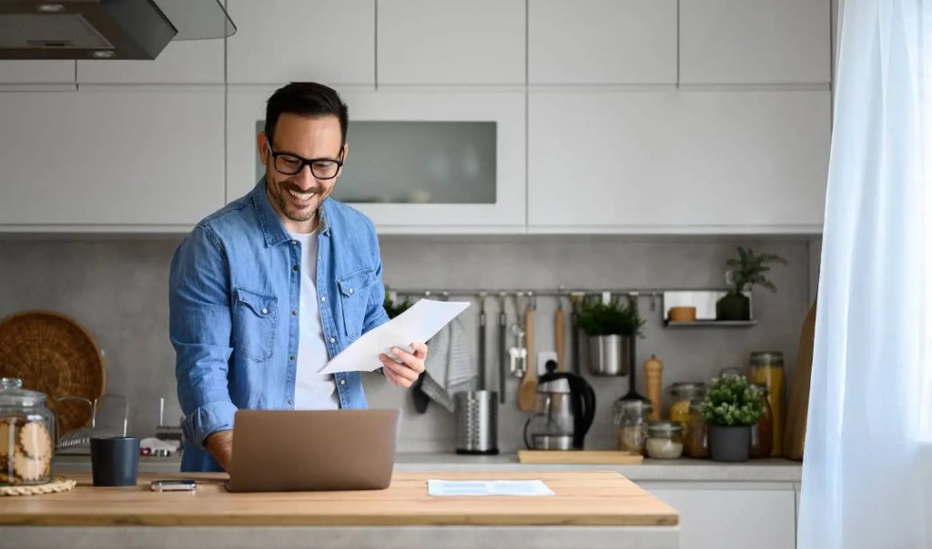 A young accountant helps small business from his home office kitchen