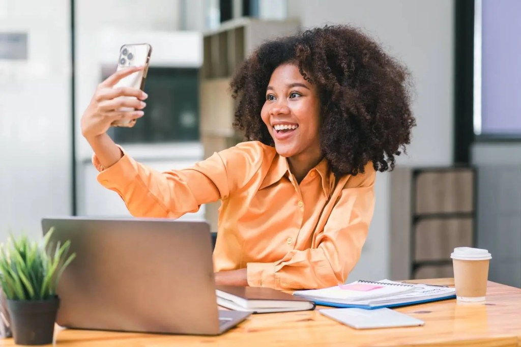 A young woman uses her cell phone to create social media content as part of her content marketing plan for a small business